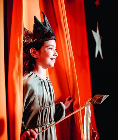 Schülerin mit selbstgebastelter Krone auf der Theaterbühne